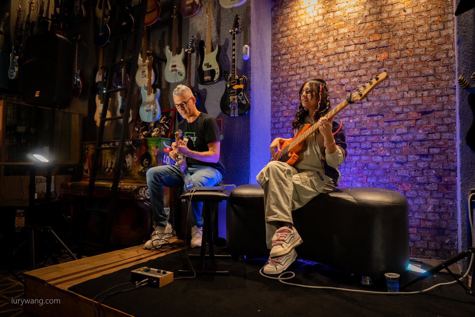 Baixista e outro músico sentados no palco da oficina da Aslan