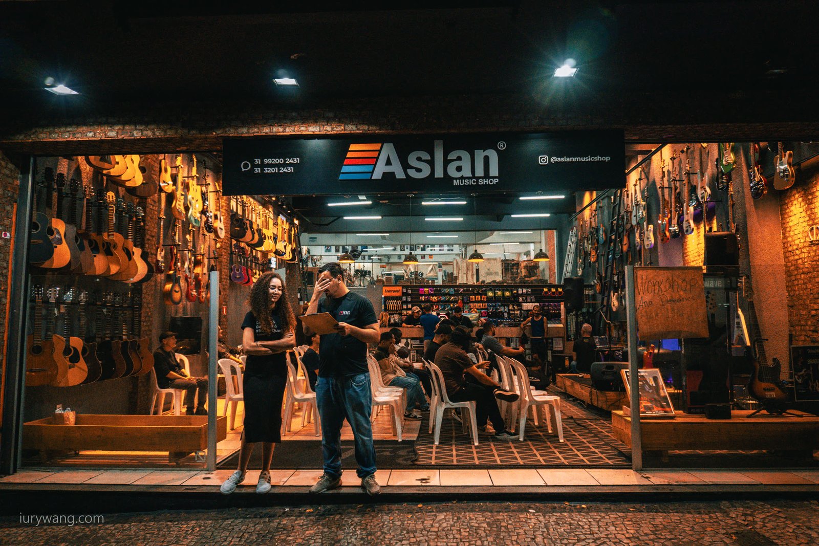 Fachada da loja Aslan à noite com pessoas na entrada