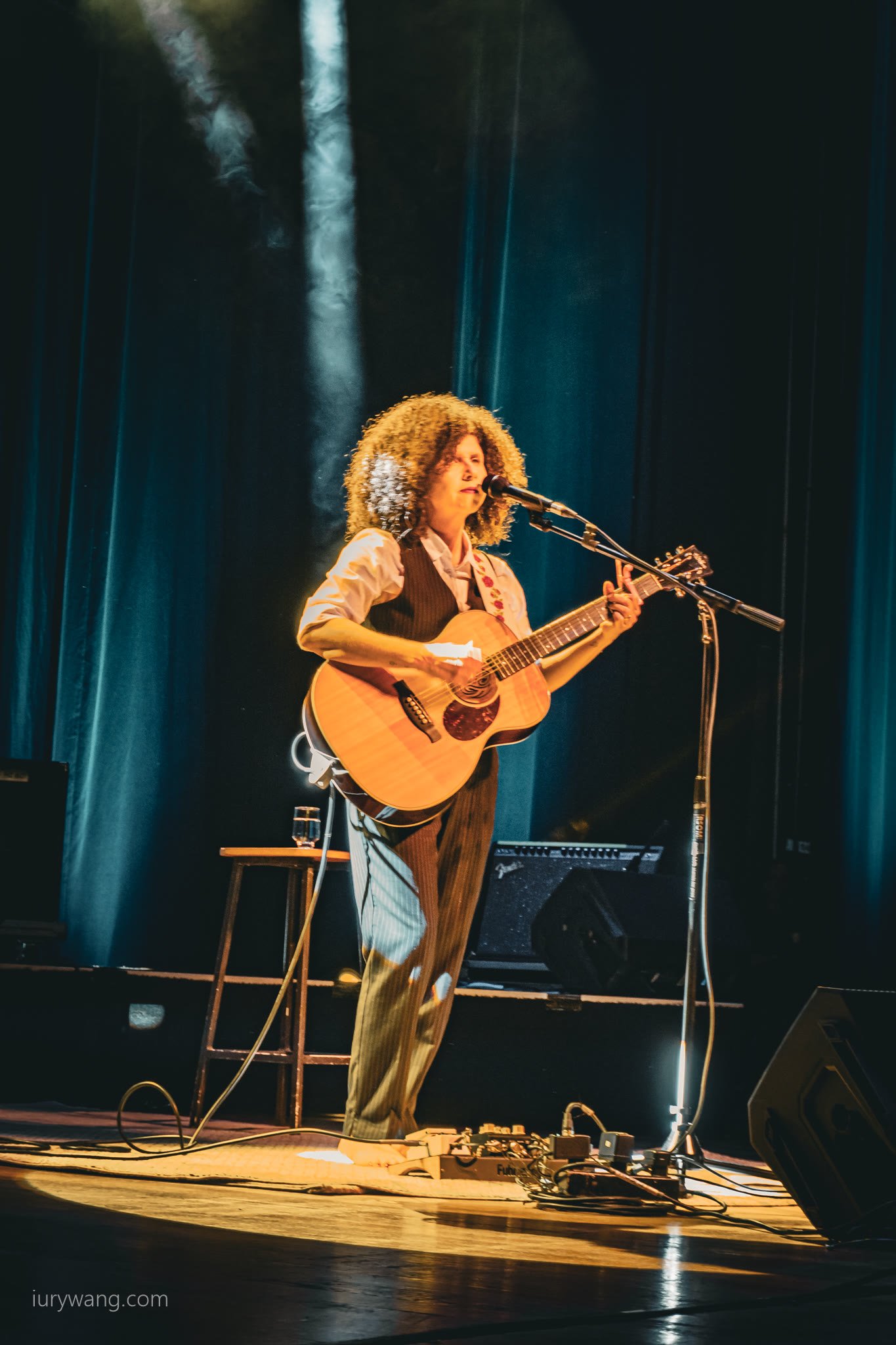 Artista ao violão e microfone sob a luz do palco do É POP BH