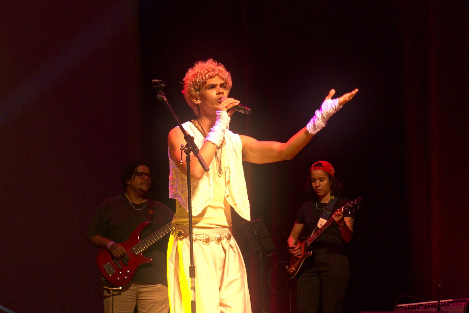 Cantor de braço aberto com banda ao fundo no É POP BH