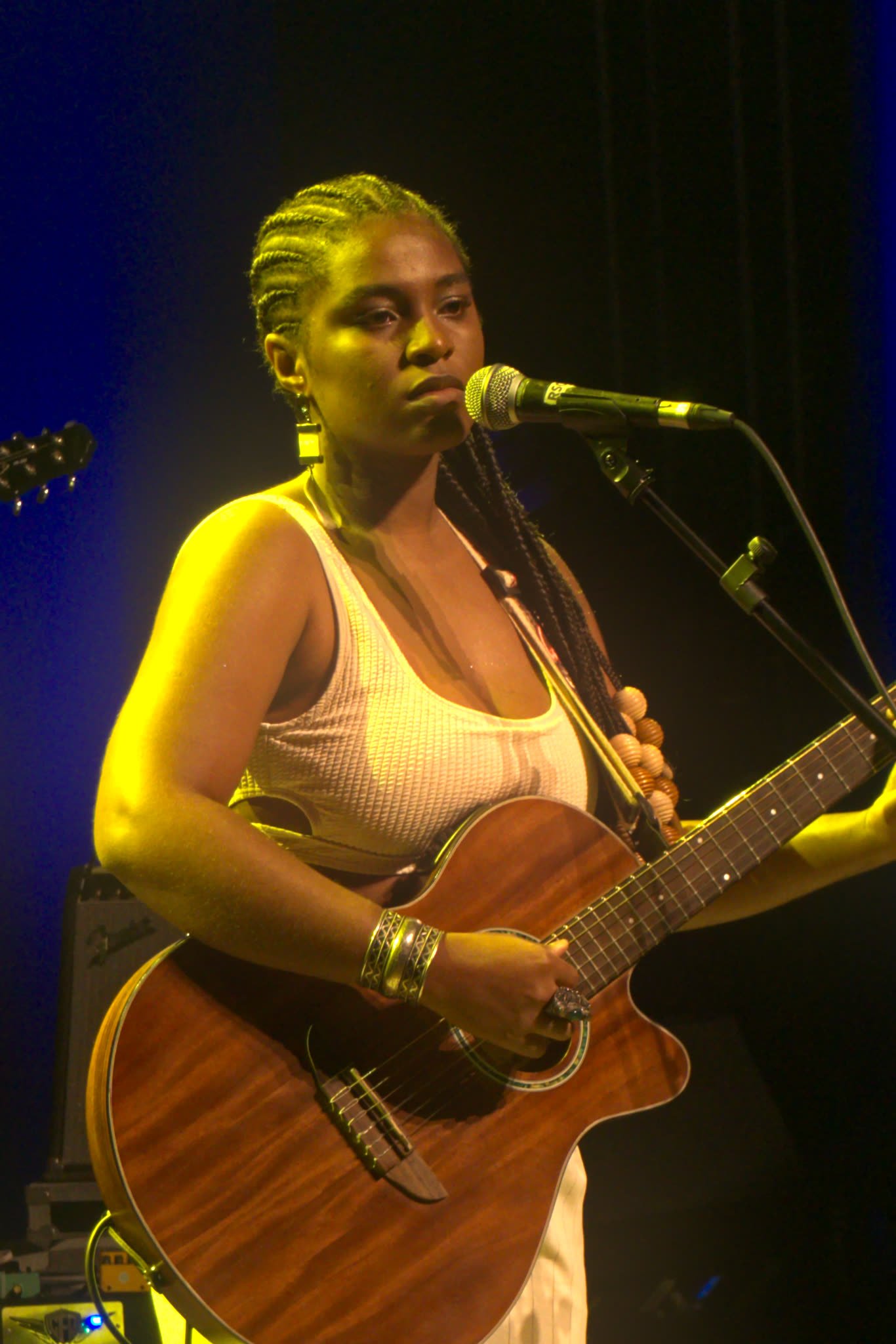 Cantora ao violão e microfone no palco do É POP BH