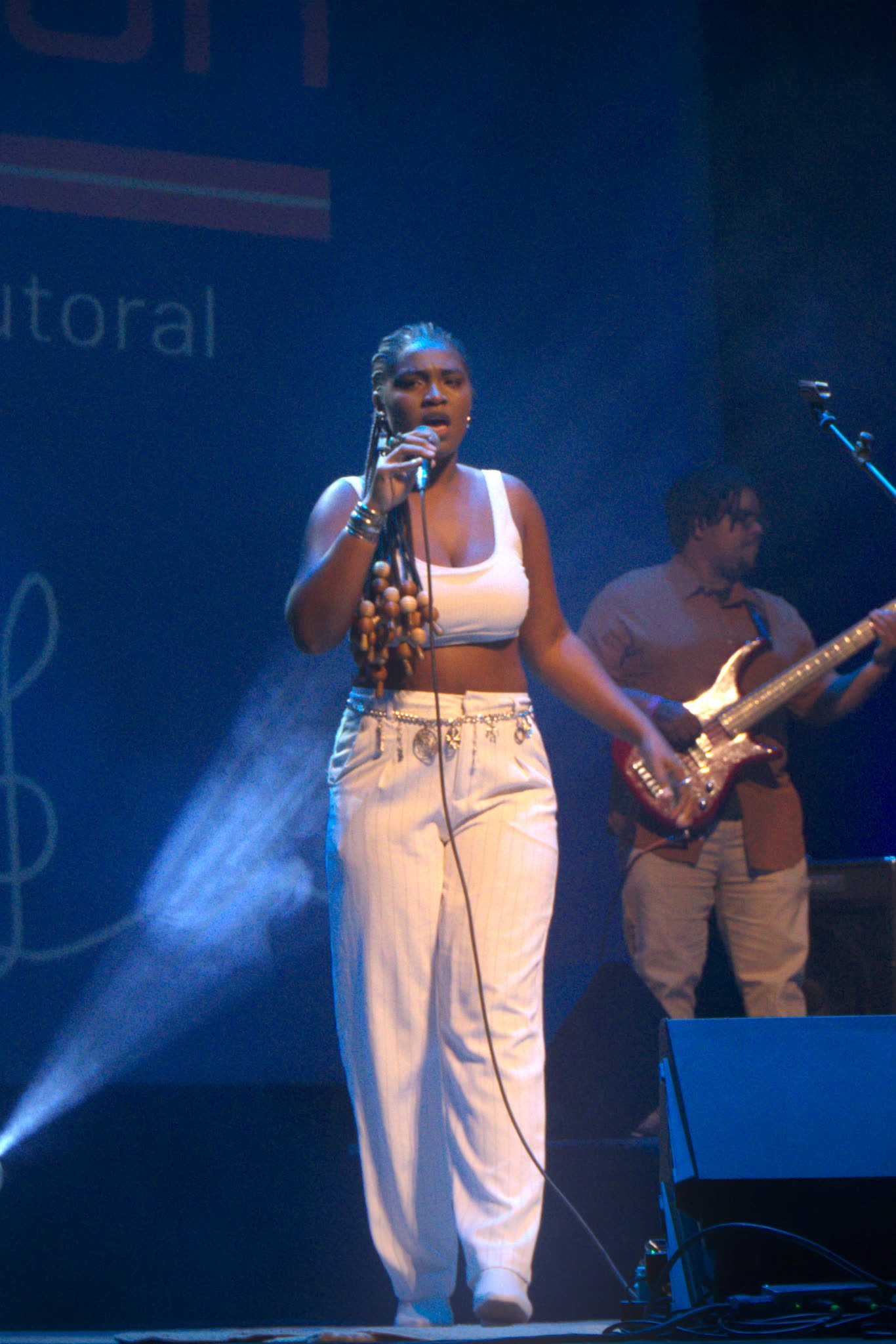 Cantora em performance com banda ao fundo no É POP BH